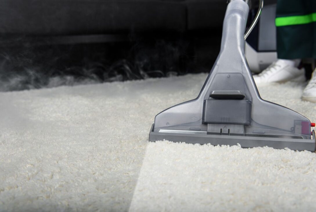 close-up view of person cleaning white carpet with professional vacuum cleaner