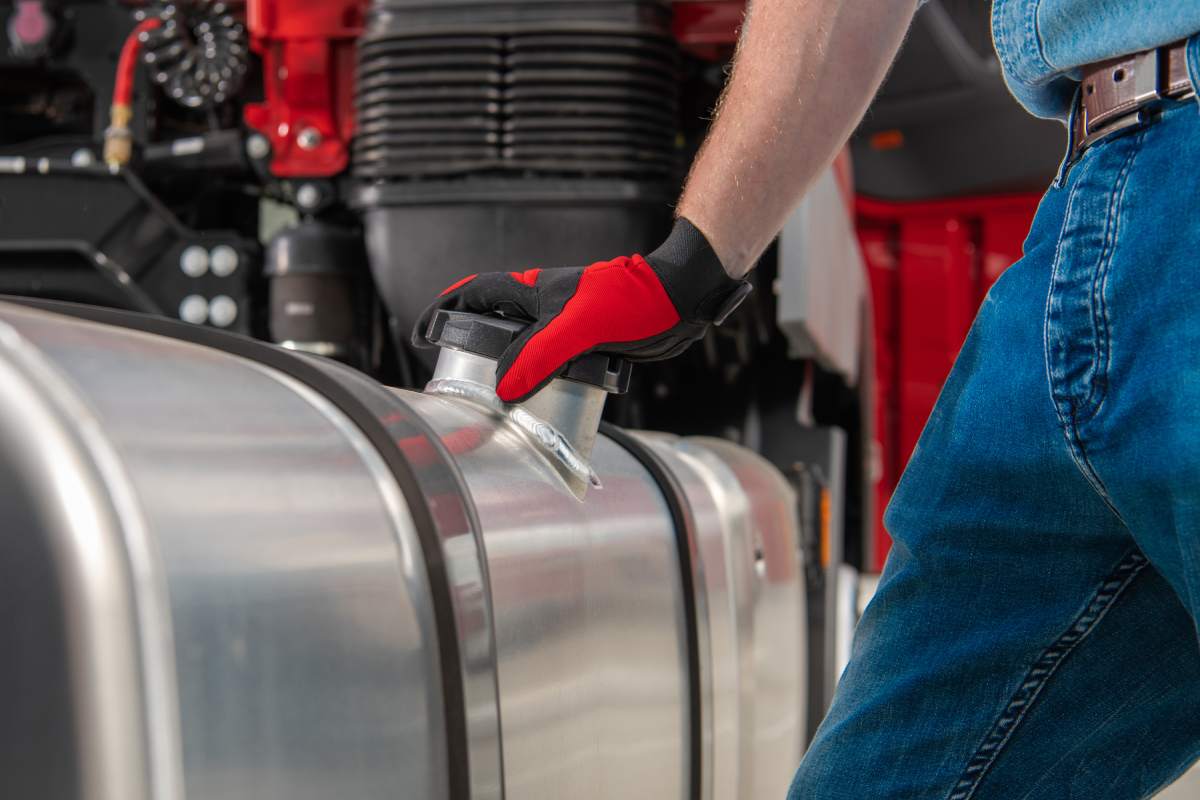 Semi Truck Side Mounted Diesel Fuel Tanks Refilling Theme. Caucasian Trucker on the Gas Station. Close Up Theme.