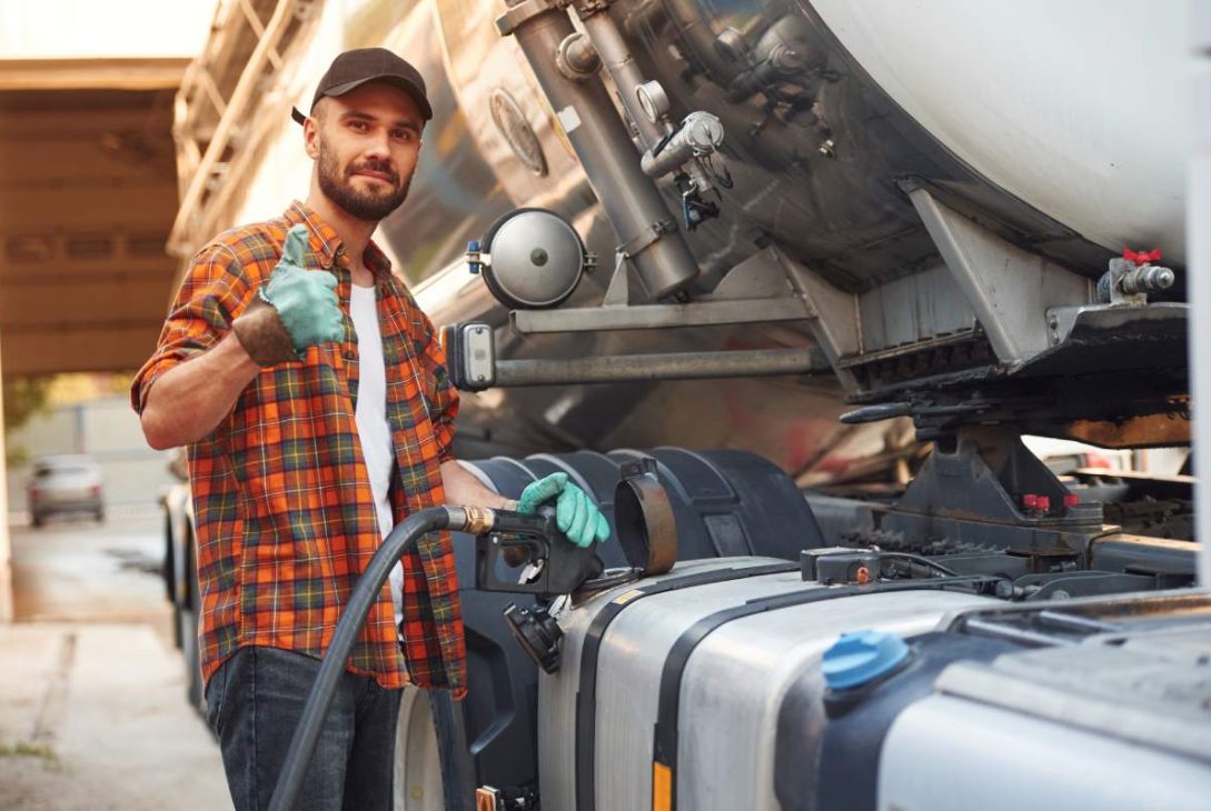 Refueling the vehicle. Young truck driver in casual clothes.