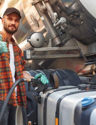 Refueling the vehicle. Young truck driver in casual clothes.