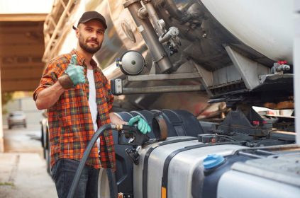 Refueling the vehicle. Young truck driver in casual clothes.