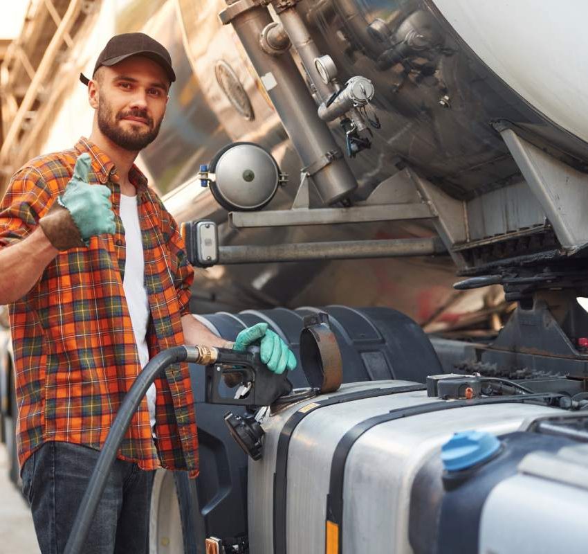 Refueling the vehicle. Young truck driver in casual clothes.