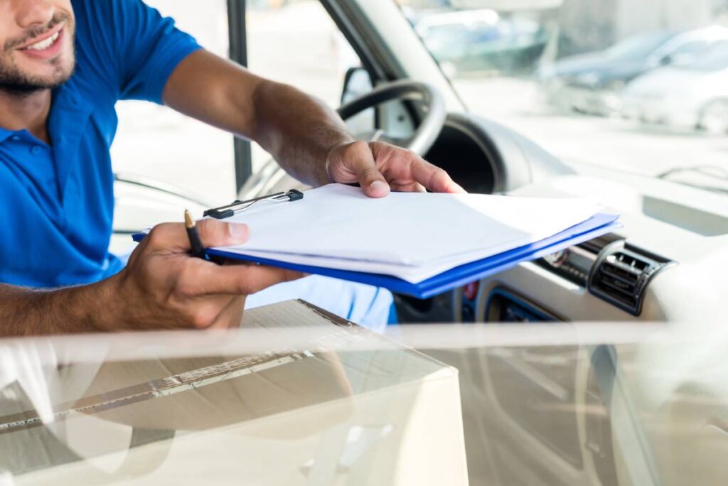 close-up shot of delivery man with clipboard sitting on van