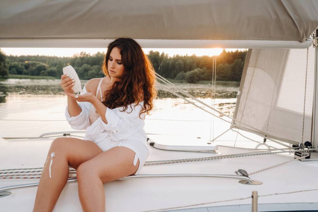 sexy woman in a white shirt spreads cream on her body on her private white yacht.